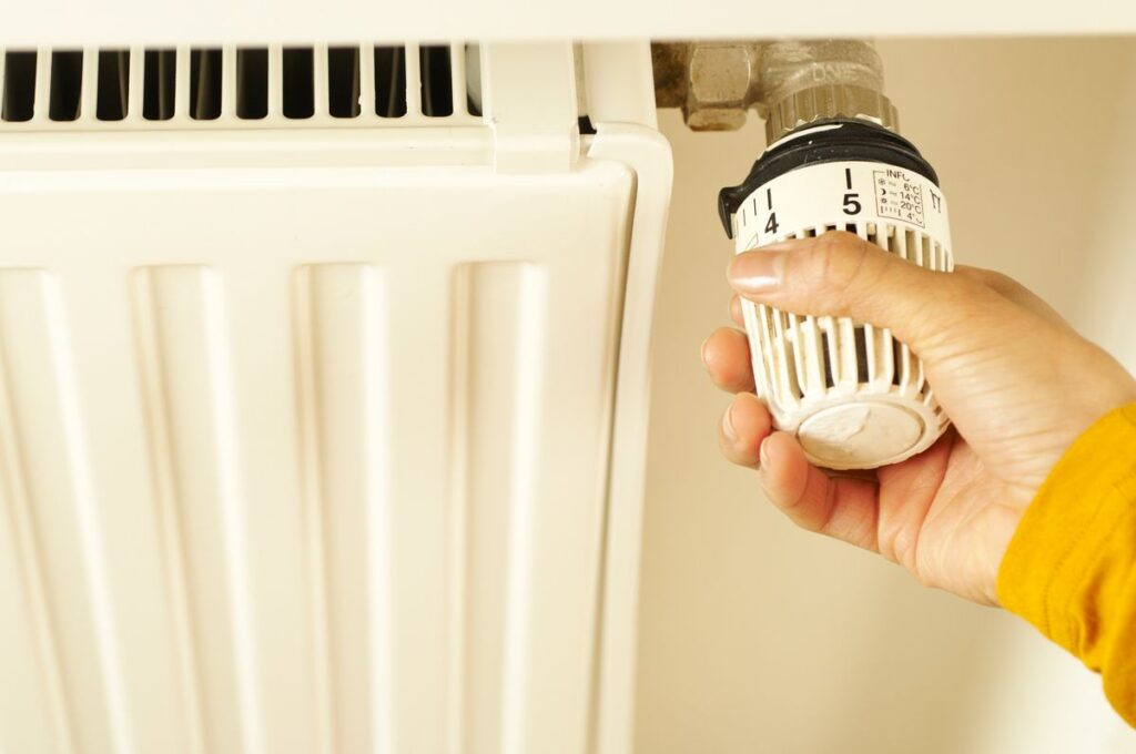Purger ses radiateurs : main réglant le robinet d'un radiateur de chauffage central